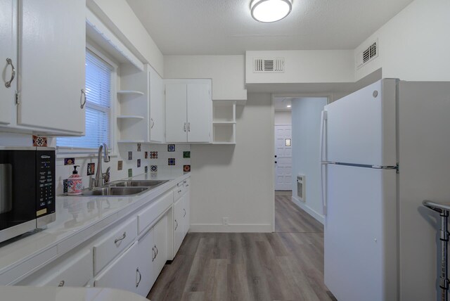 kitchen featuring visible vents, open shelves, freestanding refrigerator, a sink, and light countertops