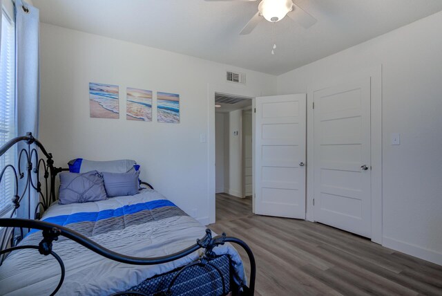 bedroom featuring a ceiling fan, multiple windows, wood finished floors, and visible vents