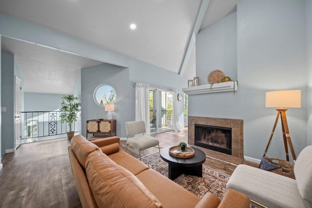 living area with a tiled fireplace, baseboards, high vaulted ceiling, and wood finished floors