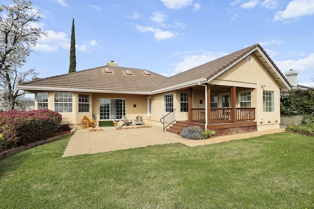 rear view of property featuring a yard, a tile roof, a chimney, and stucco siding