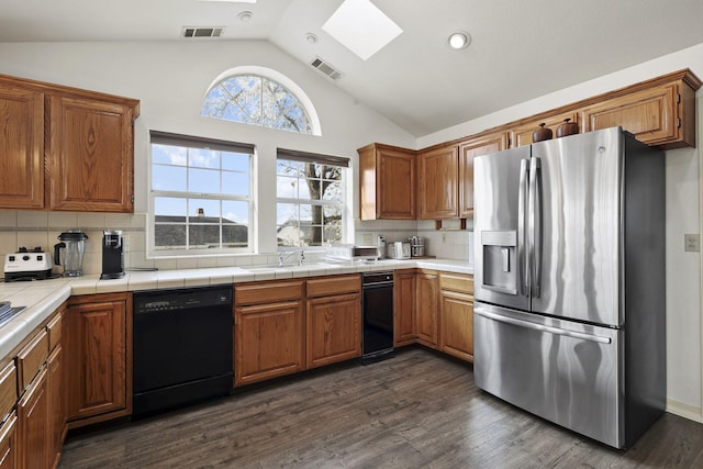 kitchen featuring visible vents, black dishwasher, dark wood finished floors, and stainless steel fridge with ice dispenser