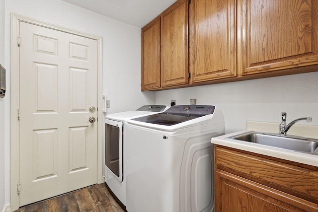 clothes washing area featuring dark wood finished floors, a sink, cabinet space, and washing machine and clothes dryer