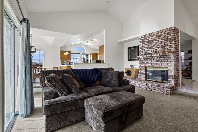 carpeted living room featuring track lighting, a fireplace, and high vaulted ceiling