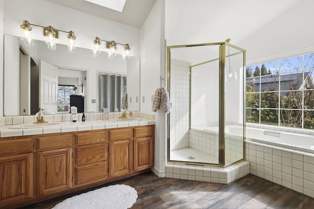 bathroom with a stall shower, wood finished floors, double vanity, and a sink