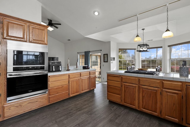 kitchen featuring tile counters, dark wood-style floors, a wealth of natural light, and oven