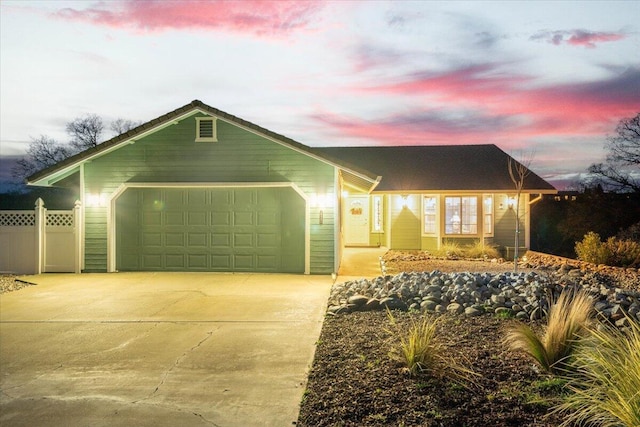 ranch-style home with concrete driveway, an attached garage, and fence