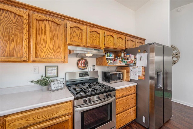 kitchen featuring brown cabinets, under cabinet range hood, dark wood-style floors, appliances with stainless steel finishes, and light countertops