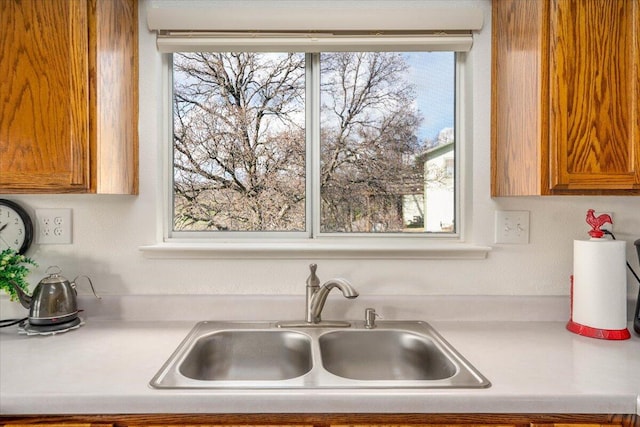 kitchen with brown cabinetry, light countertops, and a sink