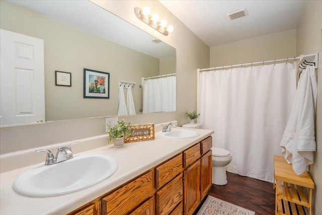 bathroom featuring toilet, wood finished floors, visible vents, and a sink