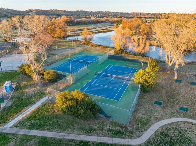 view of sport court with a water view and fence