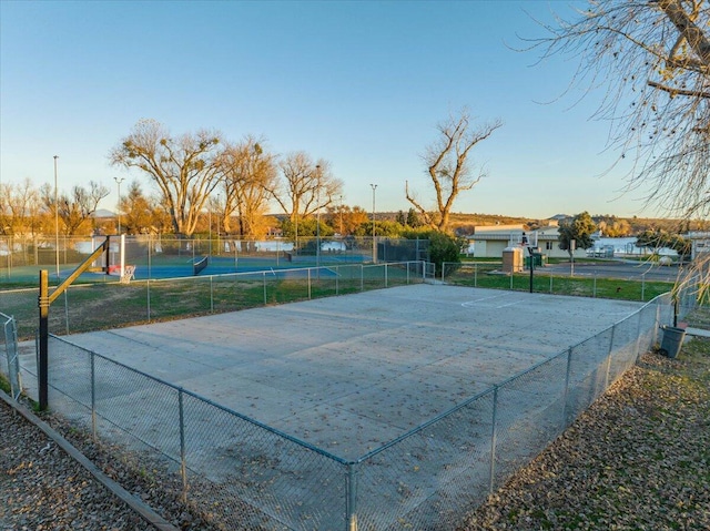 view of sport court with a water view, community basketball court, and fence