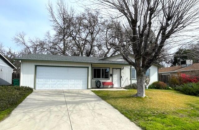 ranch-style house featuring concrete driveway, a garage, and a front yard