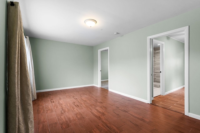 spare room featuring dark wood-type flooring and baseboards