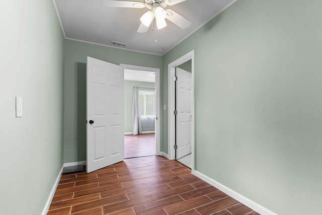 empty room featuring ornamental molding, baseboards, ceiling fan, and wood tiled floor