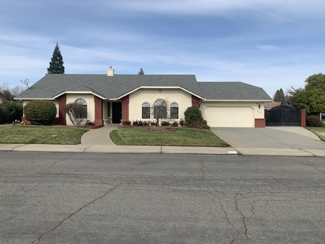 ranch-style house featuring an attached garage, concrete driveway, a front yard, and a gate