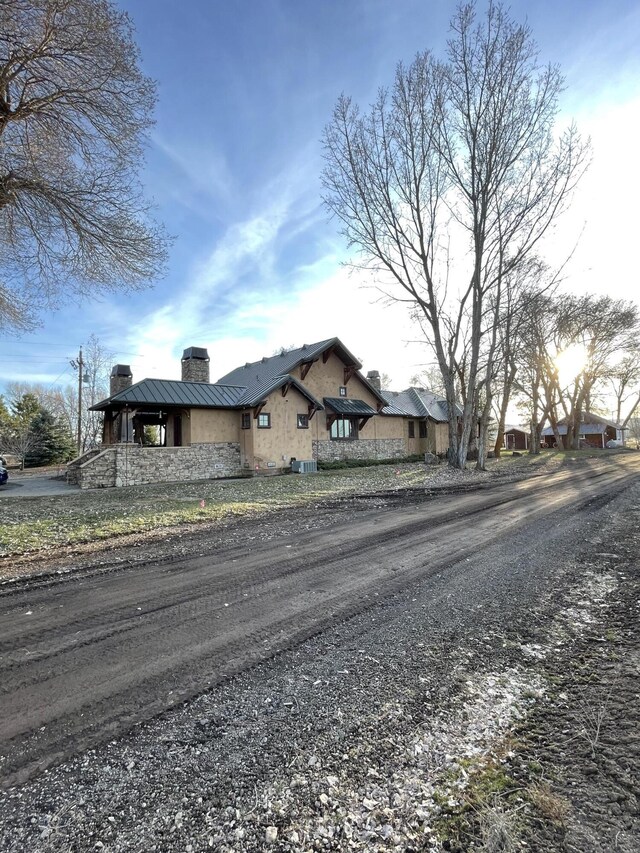 exterior space featuring stucco siding, driveway, a standing seam roof, metal roof, and a chimney