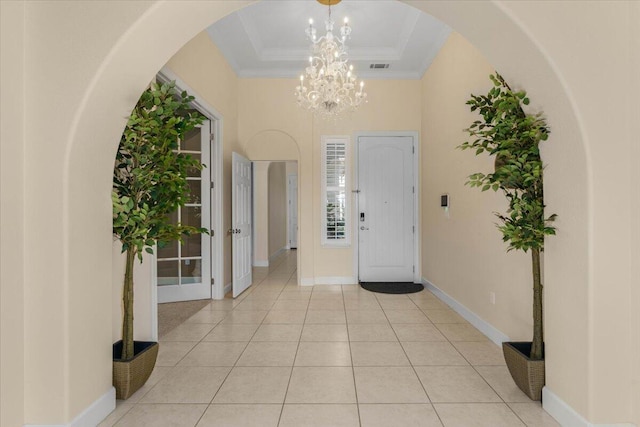 entryway featuring visible vents, a tray ceiling, light tile patterned flooring, crown molding, and baseboards