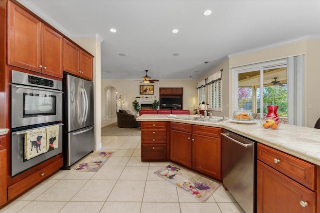 kitchen with a sink, stainless steel appliances, light tile patterned flooring, light countertops, and ceiling fan