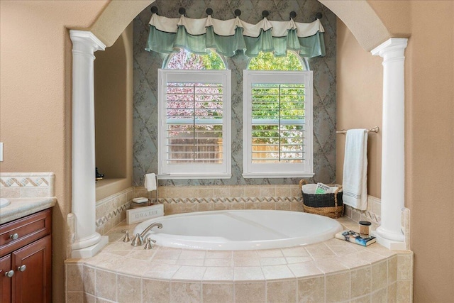 full bathroom featuring decorative columns, a garden tub, and vanity