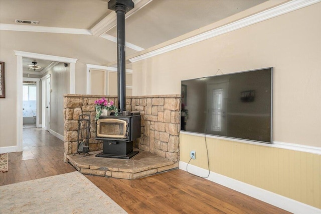 6040 Hornbeck Ln, Anderson, CA 96007 - room details with visible vents, beam ceiling, wood finished floors, crown molding, and a wood stove