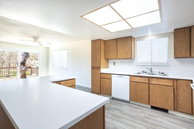 kitchen featuring dishwasher, light countertops, a textured ceiling, and a sink