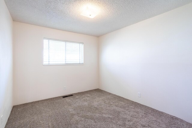 spare room with visible vents, carpet floors, and a textured ceiling