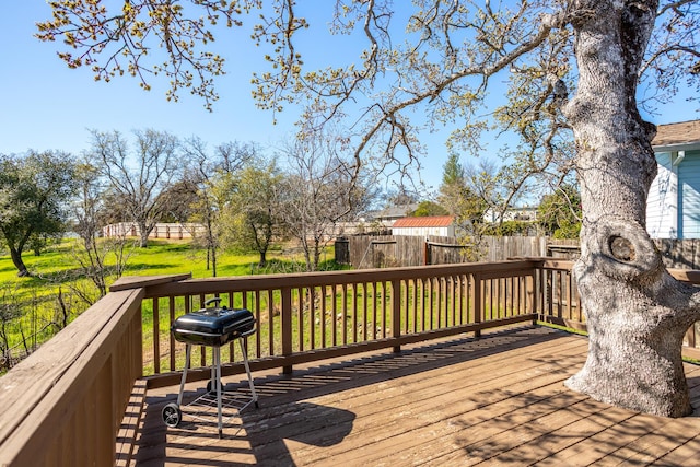 wooden terrace featuring a yard and fence