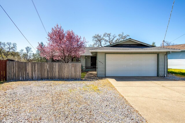 view of front of property featuring a shingled roof, concrete driveway, an attached garage, and fence