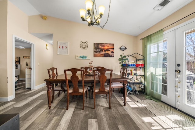 dining room featuring wood finished floors, visible vents, lofted ceiling, french doors, and a chandelier