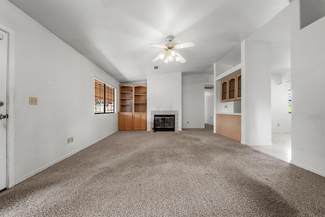 unfurnished living room with visible vents, light carpet, a ceiling fan, a tiled fireplace, and vaulted ceiling