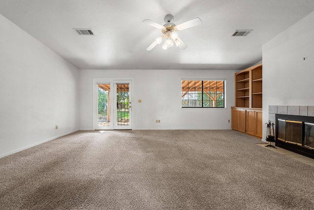 unfurnished living room with ceiling fan, a tile fireplace, visible vents, and light carpet