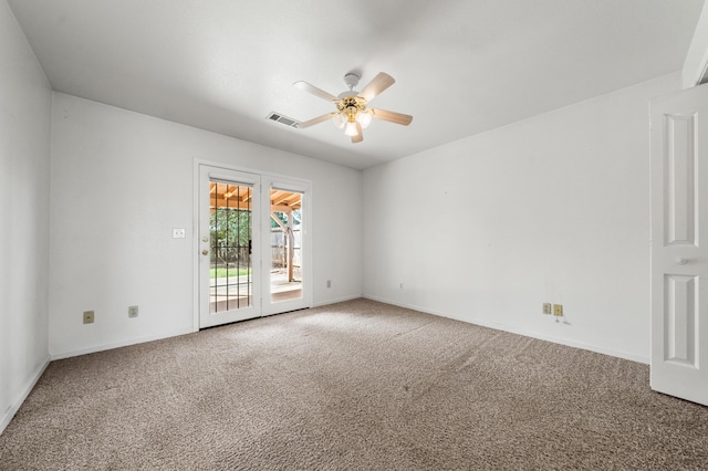 empty room with carpet flooring, a ceiling fan, visible vents, and baseboards