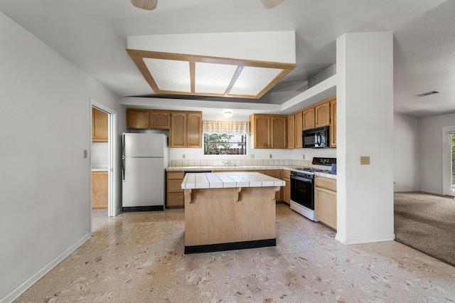 kitchen with tile countertops, visible vents, freestanding refrigerator, white gas range oven, and black microwave