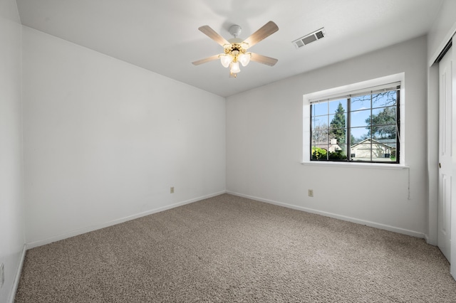 carpeted empty room with visible vents, baseboards, and a ceiling fan