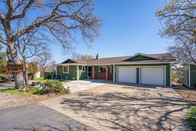 ranch-style home with brick siding, a garage, driveway, and a chimney