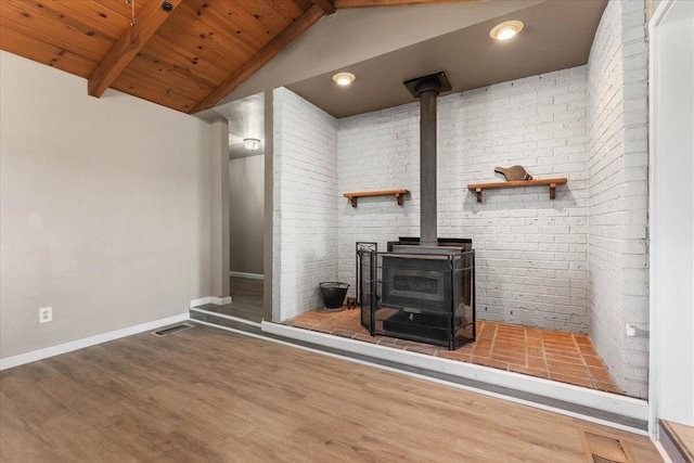 details with baseboards, beam ceiling, wood finished floors, and a wood stove