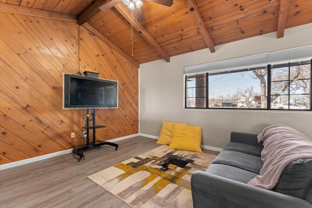 living room with a wealth of natural light, wood finished floors, vaulted ceiling with beams, and wood walls