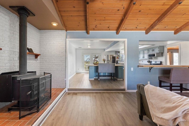 living area featuring a wood stove, vaulted ceiling with beams, and wood ceiling