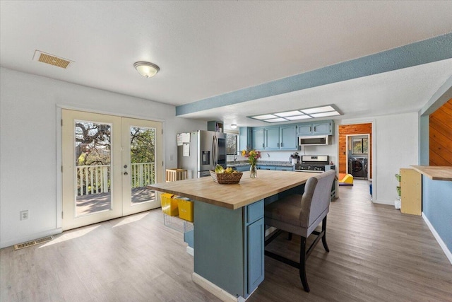 kitchen featuring butcher block countertops, visible vents, a kitchen bar, and appliances with stainless steel finishes