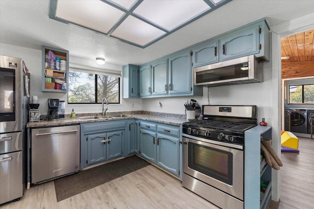 kitchen with a sink, blue cabinetry, plenty of natural light, stainless steel appliances, and separate washer and dryer