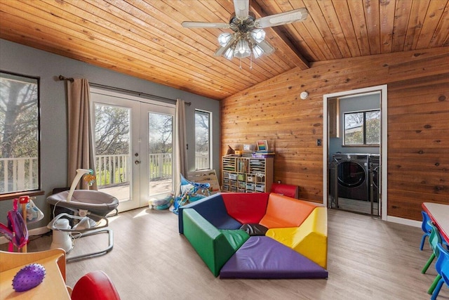 living area featuring lofted ceiling with beams, washing machine and dryer, french doors, and a healthy amount of sunlight