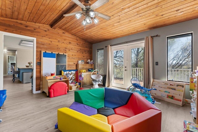 living room with wood walls, lofted ceiling with beams, french doors, wooden ceiling, and wood finished floors