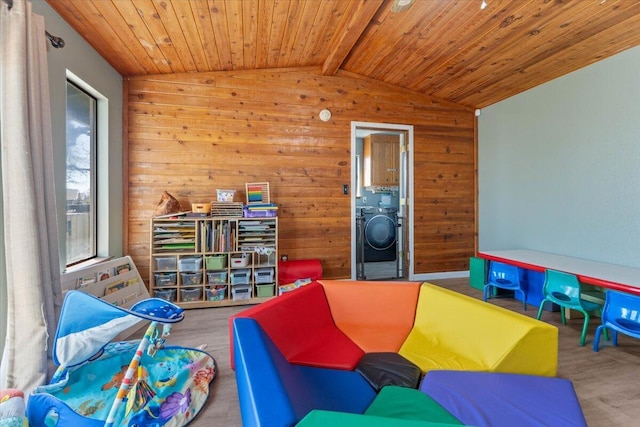 rec room with wooden walls, wood finished floors, lofted ceiling with beams, washer / clothes dryer, and wooden ceiling