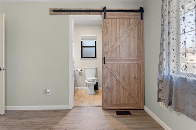 bathroom featuring toilet, wood finished floors, and baseboards