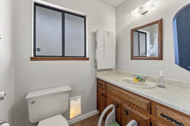 half bathroom featuring baseboards, toilet, wood finished floors, and vanity