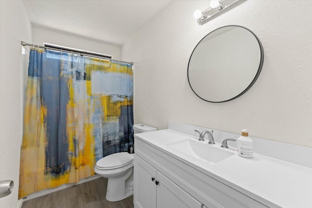 full bath featuring curtained shower, toilet, wood finished floors, a textured wall, and vanity