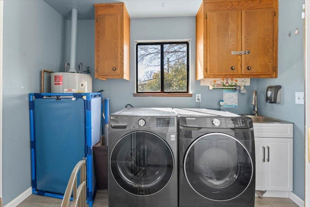 clothes washing area with washing machine and clothes dryer, electric water heater, baseboards, cabinet space, and a sink