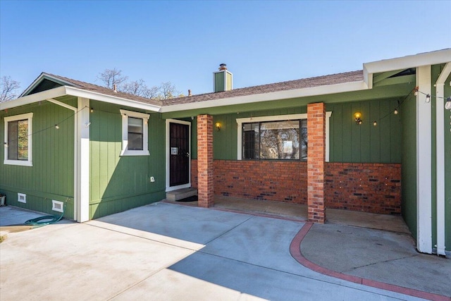 back of property with crawl space, a patio, a chimney, and brick siding