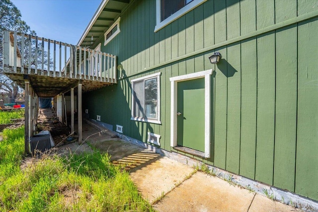 property entrance featuring board and batten siding and a wooden deck