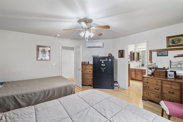 bedroom with ceiling fan, connected bathroom, light wood-style flooring, and a wall mounted AC